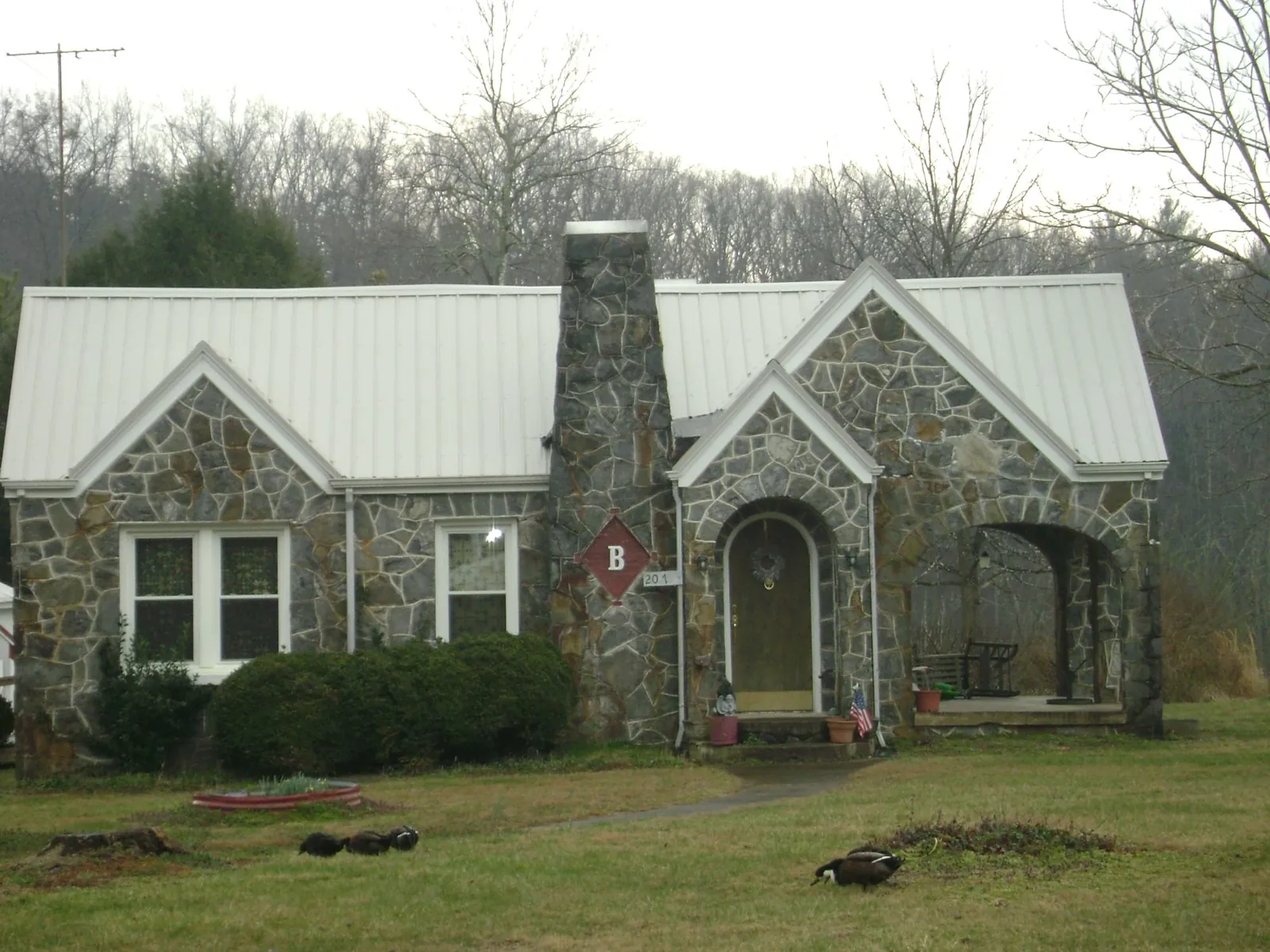 White metal roof on a stone cottage with steep gables in Saratoga
