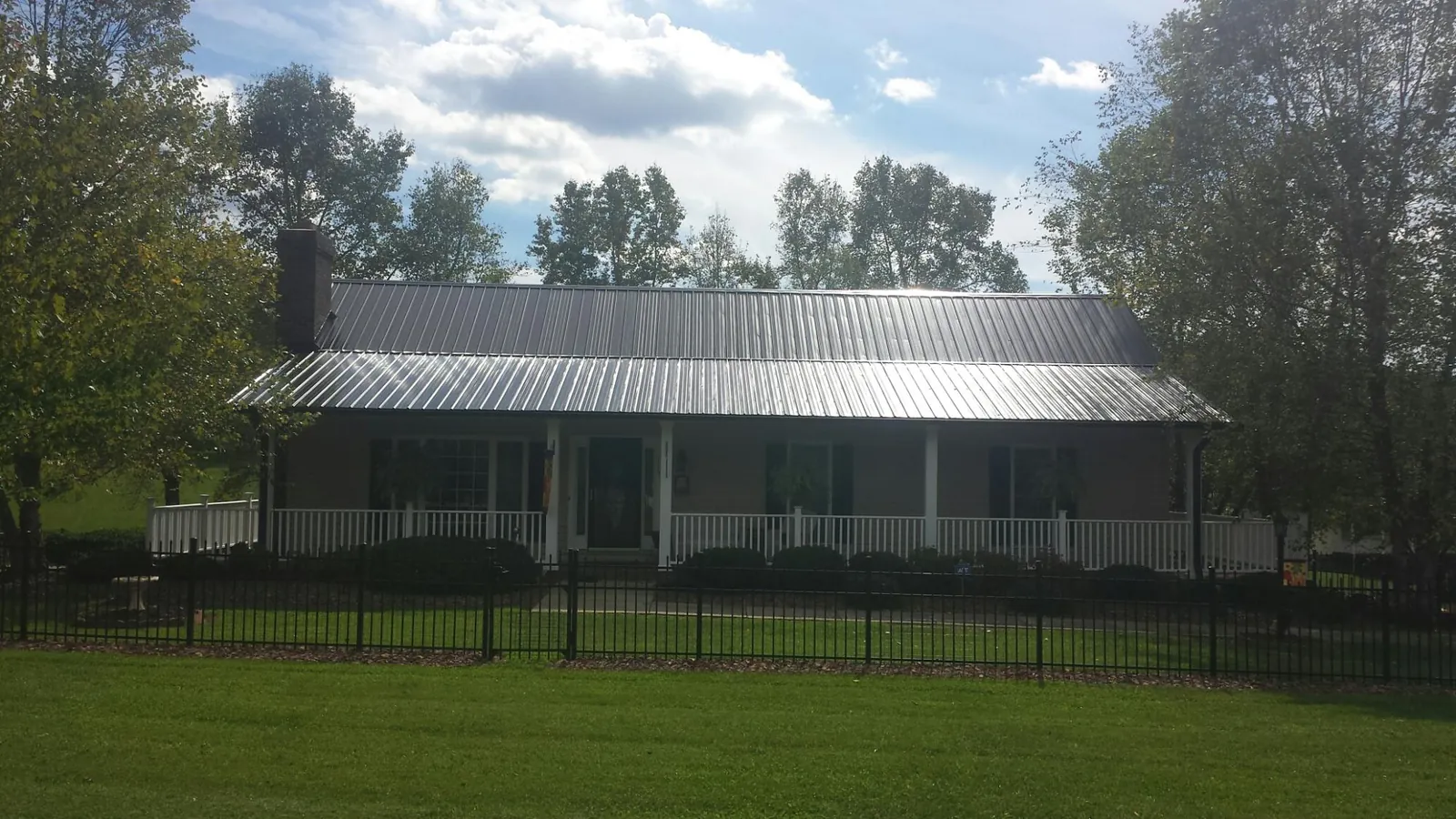 Gray metal roof on a brick ranch with a full width front porch — Gutter Guard Installation work by our crew in Saratoga